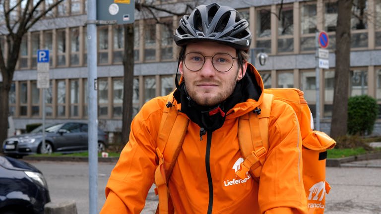 Fahrradkurier in orangener Jacke vom Lieferdienst Lieferando