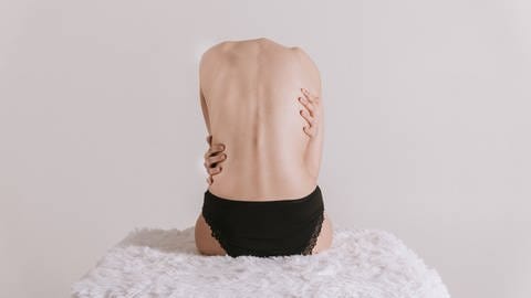 Ein Körper umarmt sich selbst: Sexologinnen und Sexualtherapeuten sind der Ansicht, dass mehr Fühlen, Spüren und Berühren heute ein Schlüssel dafür sein können, um zur eigenen Liebesfähigkeit und zum „guten Sex“ zu finden